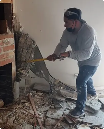 A man using a hammer to carefully remove bricks from a fireplace