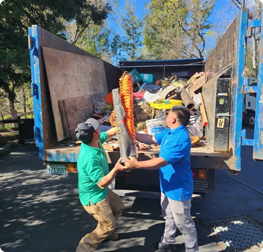 Two men are lifting a large object into the back of a truck