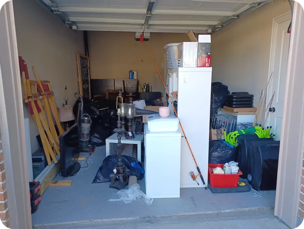 A garage interior featuring a refrigerator, a sink, and various tools and items organized on shelves