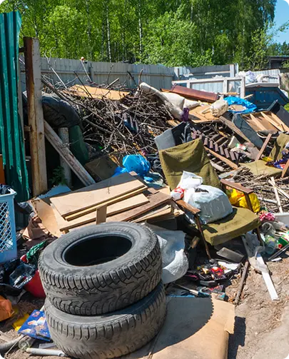 A cluttered yard filled with a pile of junk and old tires